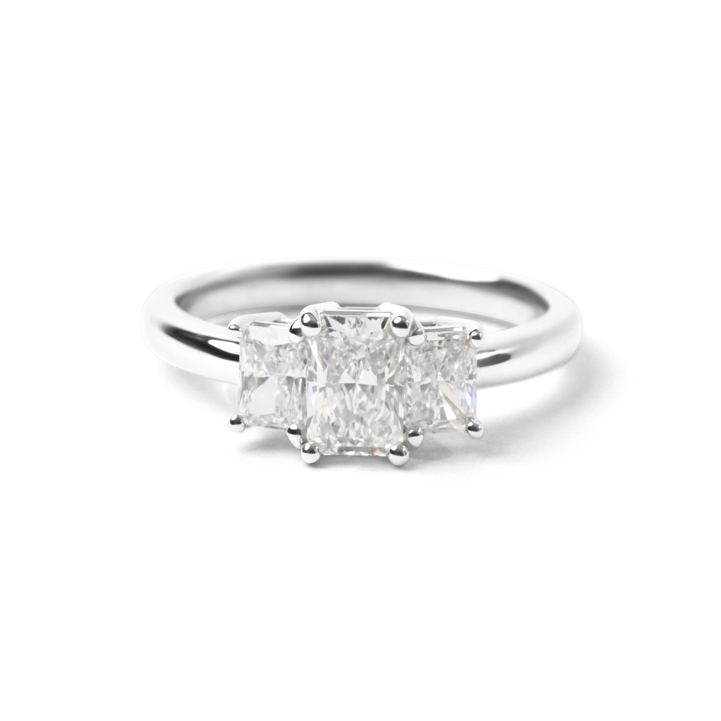 A three-stone diamond ring featuring a center radiant-cut diamond flanked by two smaller round-cut diamonds, set in a polished silver-colored band on a clean white background.