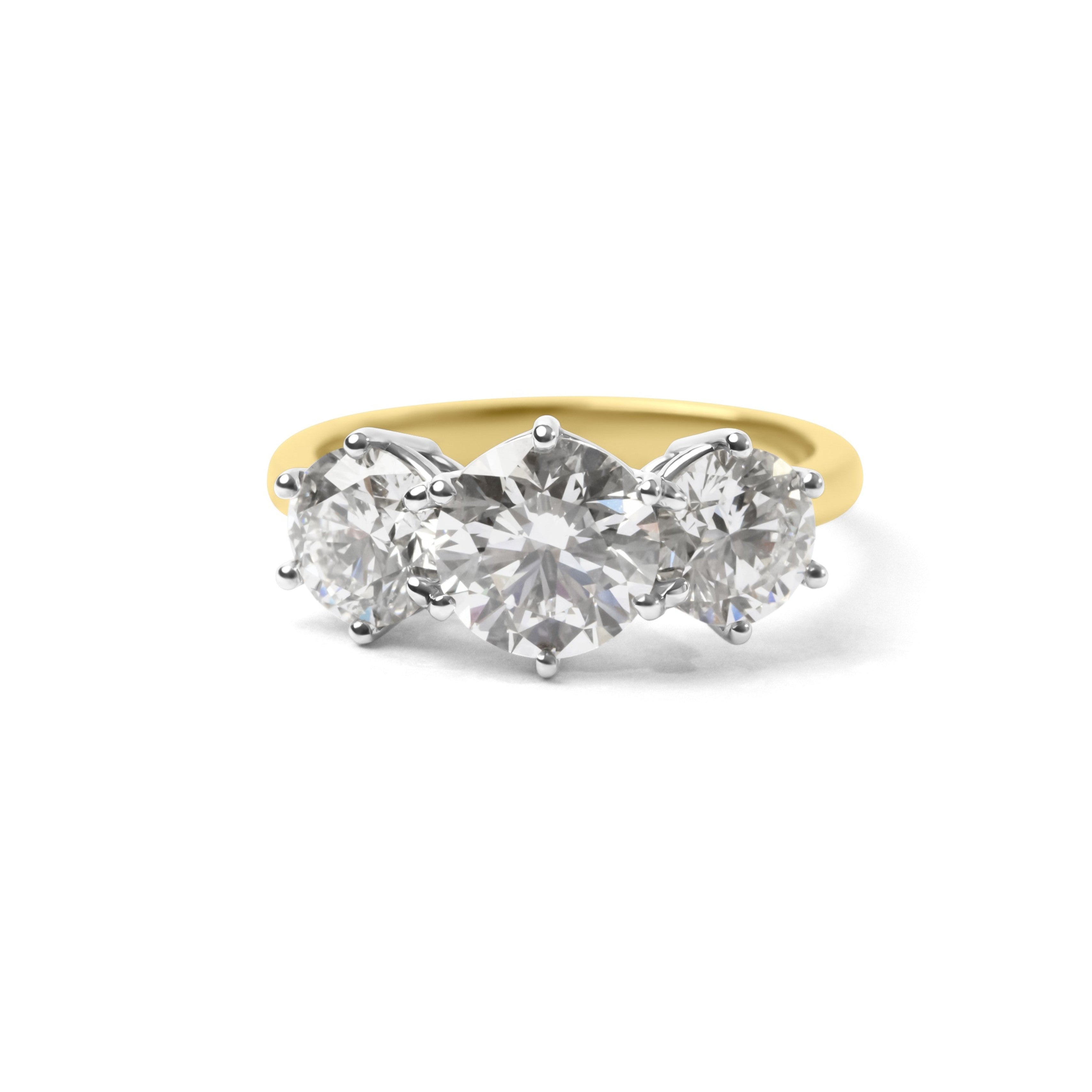 A three-stone diamond ring with a yellow gold band and silver-colored prongs, set against a plain white background.