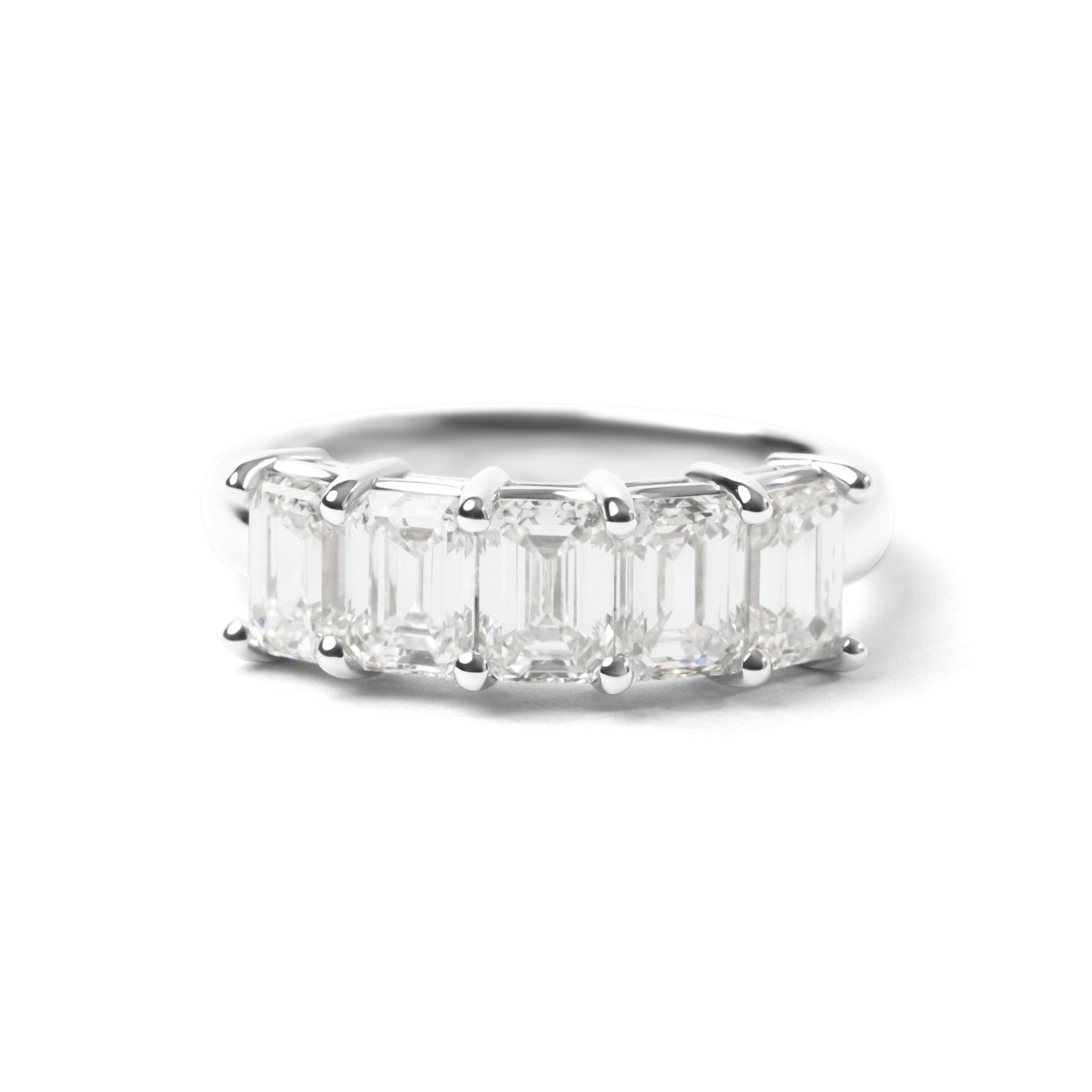 A silver band ring featuring a row of emerald-cut clear gemstones in a prong setting, shown against a plain white background.
